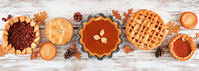 Variety of homemade autumn pies. Apple, pumpkin and pecan. Top view table scene on a white wood banner background.