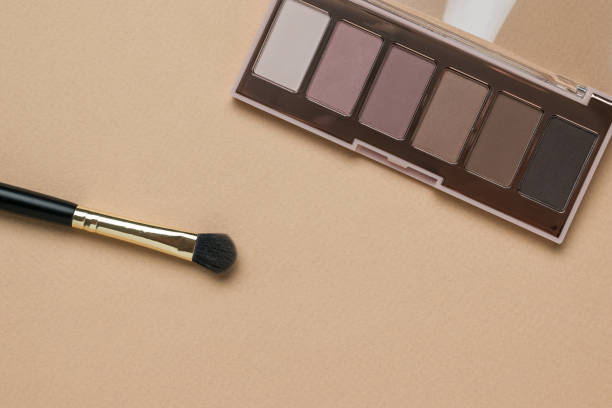 istock A makeup brush and an open set of eye shadow on a beige background. 1345858532