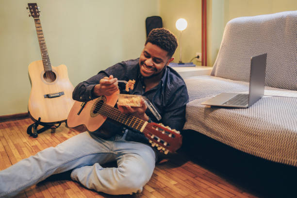 istock Afro-American eating during guitar playing practice at home 1345859058
