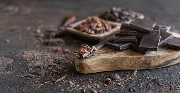 istock Composition of chocolate pieces, drops and chips on dark concrete background. Background with different kind of chocolate. 1345863795