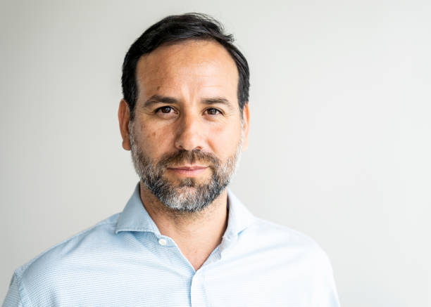 Portrait of a confident businessman with beard Portrait of a confident businessman with beard against grey wall. Male entrepreneur in shirt looking at camera. headshot stock pictures, royalty-free photos & images