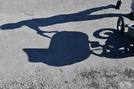 Shadow of a woman driving a baby carriage on an asphalt background, Slovenia, Europe. Nikon D850.