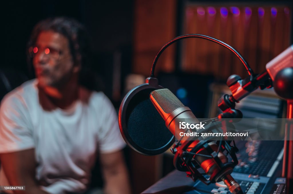 Microphone in music studio Microphone in music studio with the music producer sitting in the background Radio Stock Photo