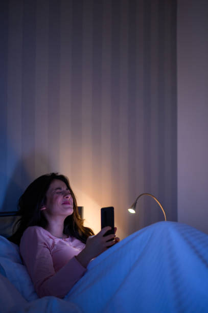 istock Woman lying in her bed during night and using a smartphone 1345867778
