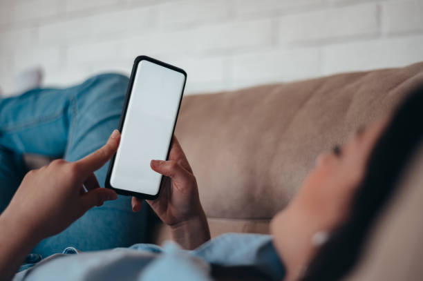 istock Woman using smartphone while lying on the couch at home 1345867781