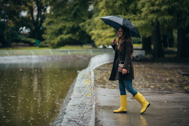 istock Woman holding an umbrella while walking in the park 1345867796