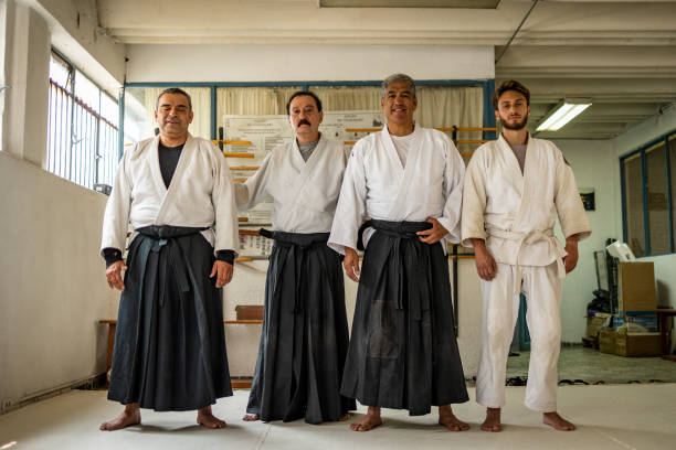 Low angle of a four people in kimonos Four men standing and looking at the camera. Aikido class mixed martial arts photos stock pictures, royalty-free photos & images
