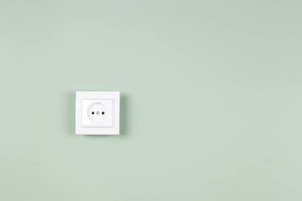 istock White electric socket on yellow background. One electrical outlet on the wall 1345871188