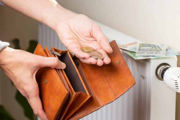 la mano de la mujer toma dinero en euros de la billetera y coloca la batería del radiador de calefacción con regulador de temperatura. costos de calefacción caros durante la temporada de frío. pago de facturas - gas prices energy crisis environment finance fotografías e imágenes de stock