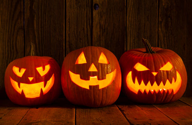 istock Three Spooky carving Halloween pumpkins on wooden plank. 1345871438