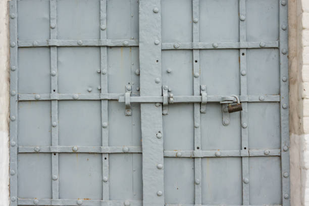 Antique wrought iron door in a stone building. The locking device is padlocked. Background. Texture.