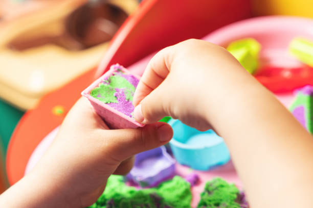 istock Hands of a child playing with multicolored kinetic sand 1345875994