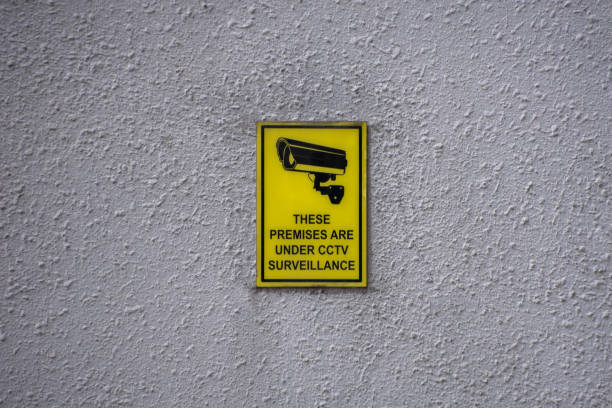 CCTV security sign on a wall A security sign on outdoor building wall which warns that CCTV cameras and alarm systems are in operation 24 hours a day. surveillance camera sign stock pictures, royalty-free photos & images