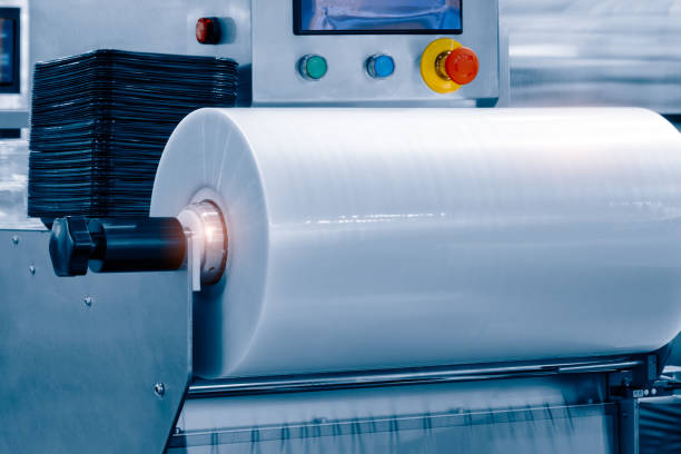 istock The operation of automatic plastic bag production machine with lighting effect. Close-up of the roller of the plastic bag production machine in the light blue scene. 1345880468