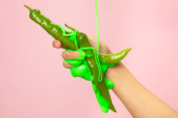 istock Hand Holding Sliced green peppers on pink paper background. 1345882940