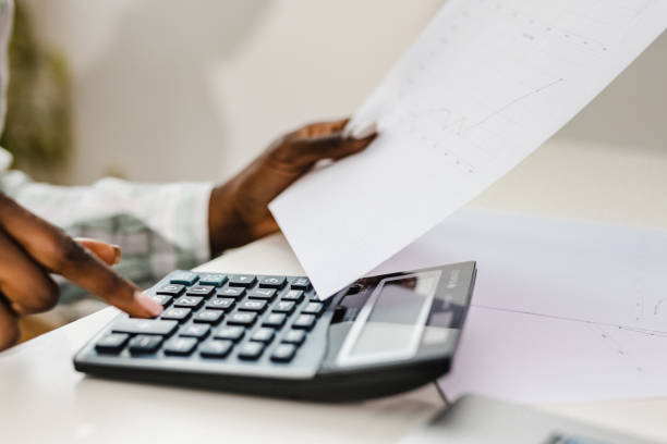 istock Human hand using a calculator and holding a paper 1345886470