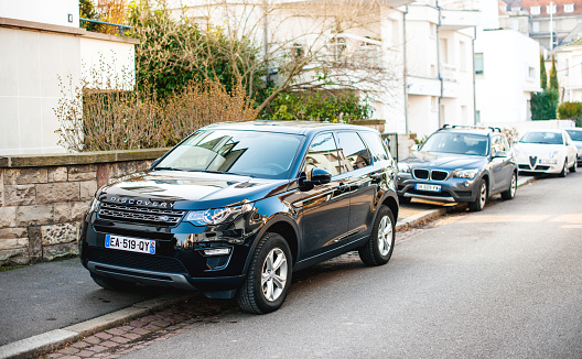 Strasbourg, France - Feb 13 2017: New luxury Land Rover Discovery executive SUV parked on a French street with multiple cars parked in background
