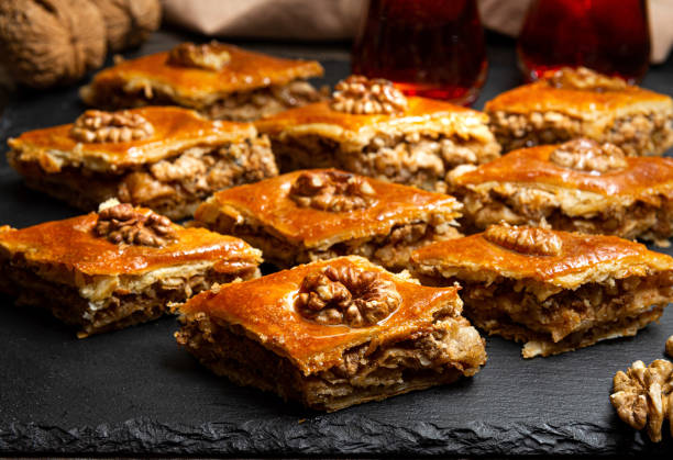 Honey baklava with walnuts on black slate. Portions of oriental sweets. Turkish sugary pieces. stock photo