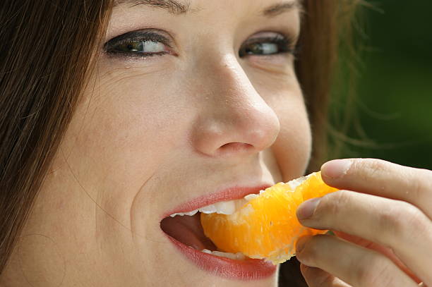 istock Pretty Girl eats Orange Outside Picnic Biting Fruit Slice Midway 134589246