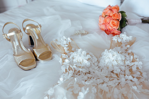 Beautiful white wedding dress and shoes for bride indoors. Beauty of bridal gown for marriage. Female lace clothes for celebration