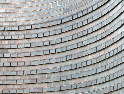 close up of a curved grey brick wall with raised rows forming a pattern