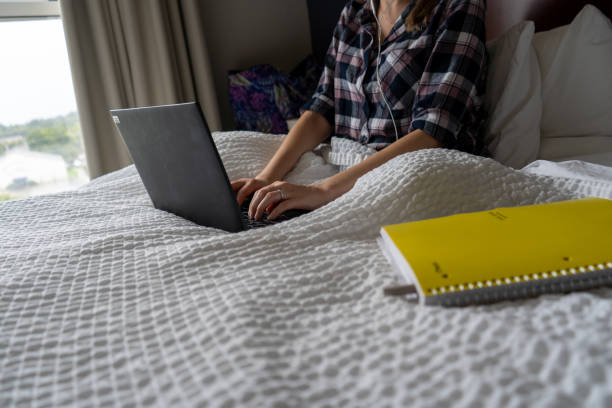 istock Lady Works From Home Remotely in Bed with Laptop and Notebook 1345895441