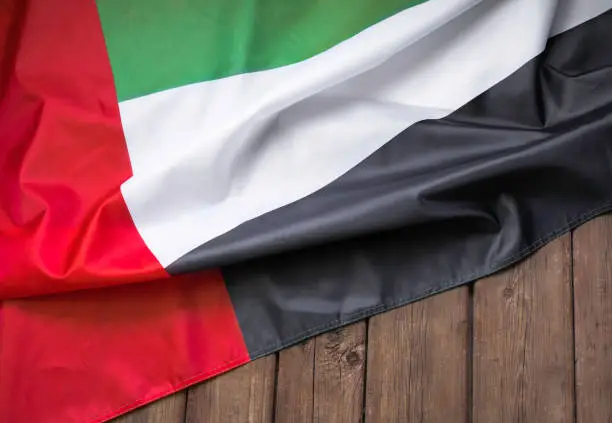 Photo of Flag of the United Arab Emirates and place for text on a dark wooden background