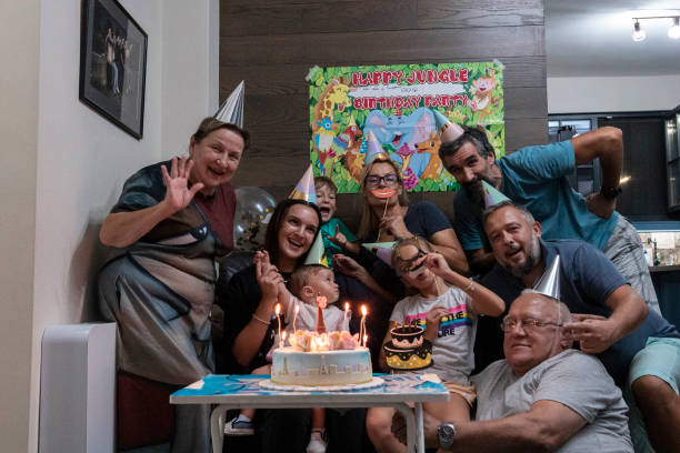 Birthday party with the family during COVID-19. Blowing candles on a birthday cake. A 9-year-old girl celebrates with the whole family and cousins in pandemic times. happy birthday cousin images stock pictures, royalty-free photos & images
