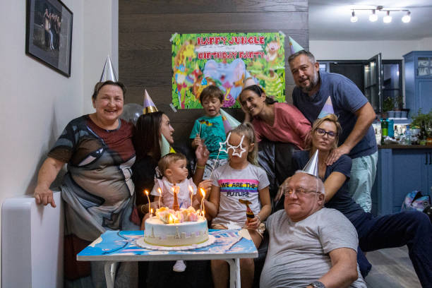 Birthday party with the family during COVID-19. Blowing candles on a birthday cake. A 9-year-old girl celebrates with the whole family and cousins in pandemic times. happy birthday cousin images stock pictures, royalty-free photos & images