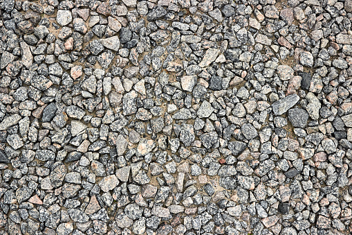 Small stone texture or gravel for background or design. Dark grey closeup small rocks. Real grunge texture background and small stone. Pebbles stone texture seamless texture. Top view of ground gravel road.
