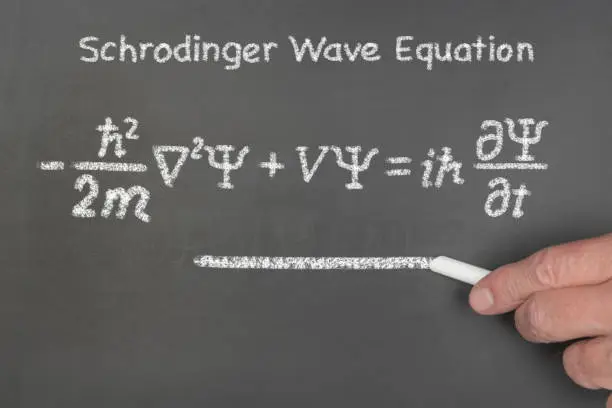 A teacher explains to students the principles Schrodinger's linear partial differential wave function equation, a key element of quantum mechanics.