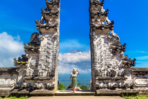 Woman traveler at  Ancient gate at Pura Penataran Agung Lempuyang temple and volcano Agung on Bali, Indonesia