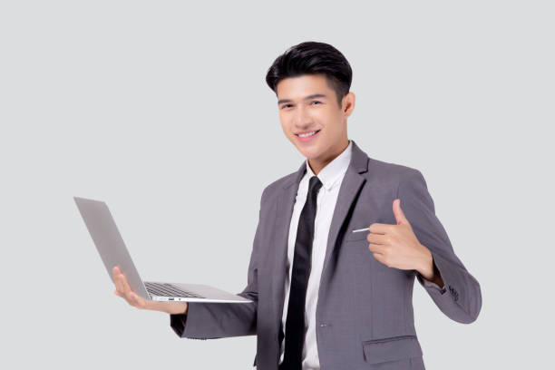 istock Young asian business man standing work on laptop computer to internet online isolated on white background, businessman confident and notebook, freelance with success, marketing and communication. 1345916178