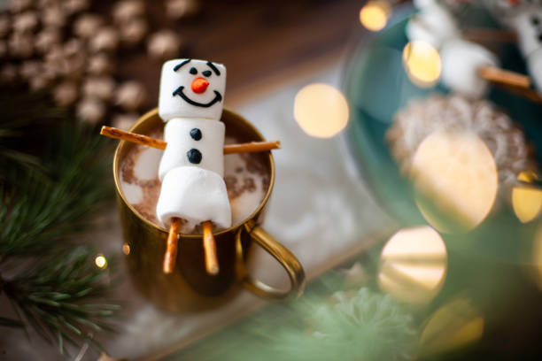 istock A marshmallow snowman decorated with icing. Gold mug with cocoa and Christmas decor. Gingerbread in the form of snowflakes 1345918017