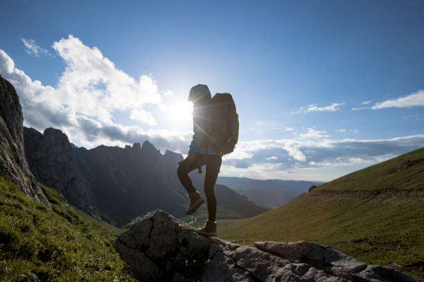 istock Successful woman backpacker hiking on sunset alpine mountain peak 1345919729