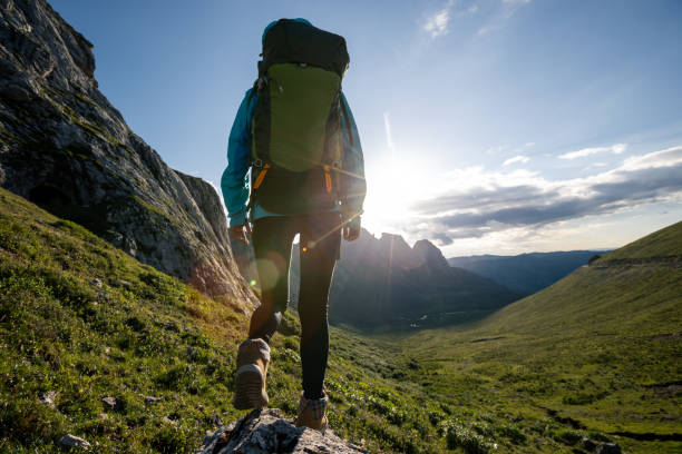 istock Successful woman backpacker hiking on sunset alpine mountain peak 1345919774