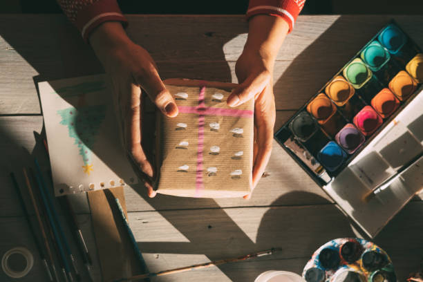Hands holding a gift with the wrapping painted with watercolors