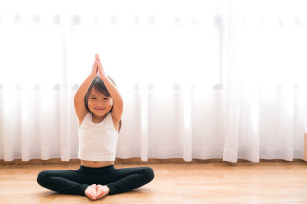 Asian little cute girl doing yoga at home stock photo