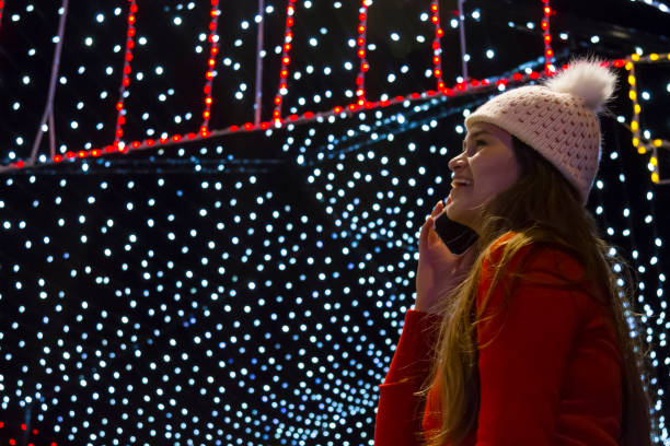 istock Young woman walking around downtown while talking by cellphone / smartphone with her relatives for Christmas Holidays using 5G Technology 1345924228