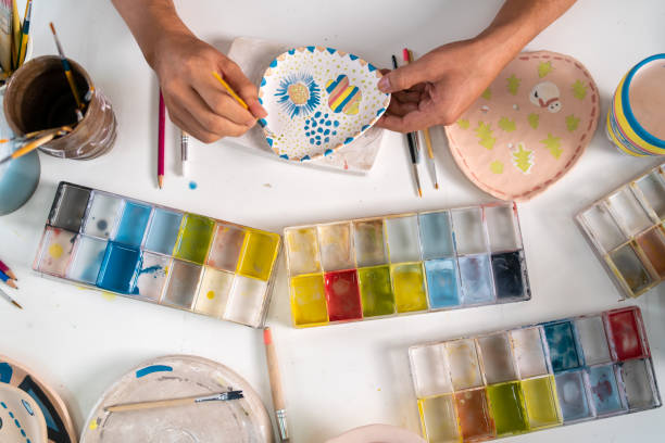 istock Asian LGBTQ guy painting self-made pottery at home studio. 1345924355
