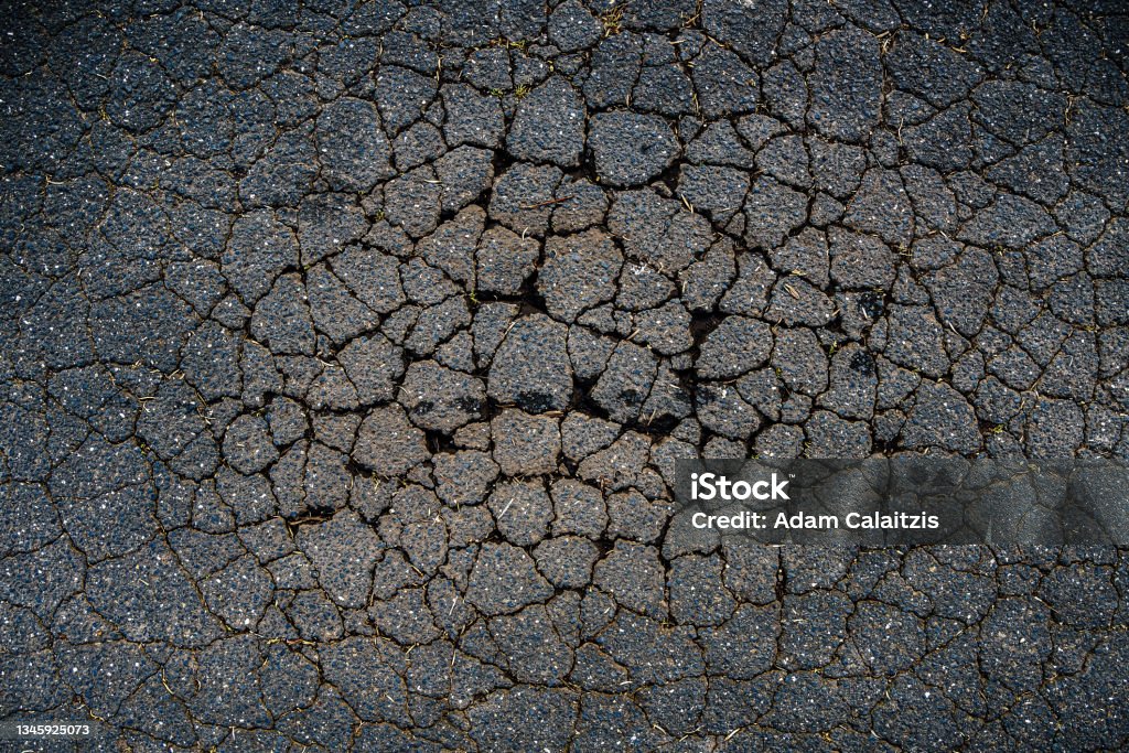 A cracked bitumen public road surface A cracked bitumen public road surface forming a natural pattern Pot Hole Stock Photo