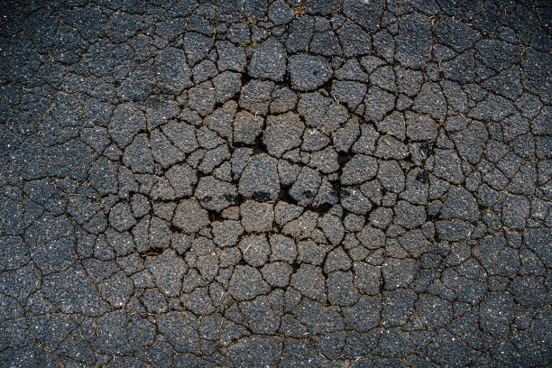 A cracked bitumen public road surface A cracked bitumen public road surface forming a natural pattern sinkhole stock pictures, royalty-free photos & images