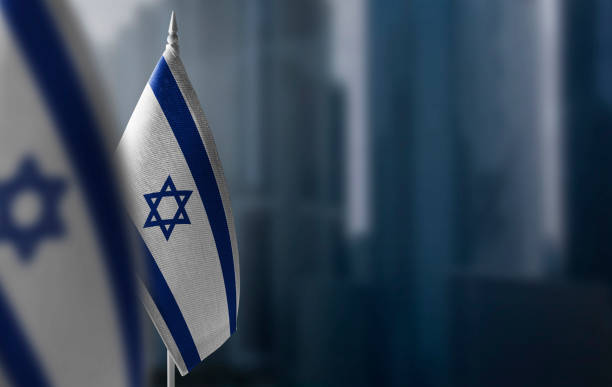 small flags of israel on a blurry background of the city - israël stockfoto's en -beelden