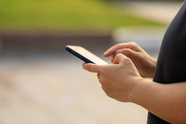 istock Asian woman using smartphone outdoors 1345932038