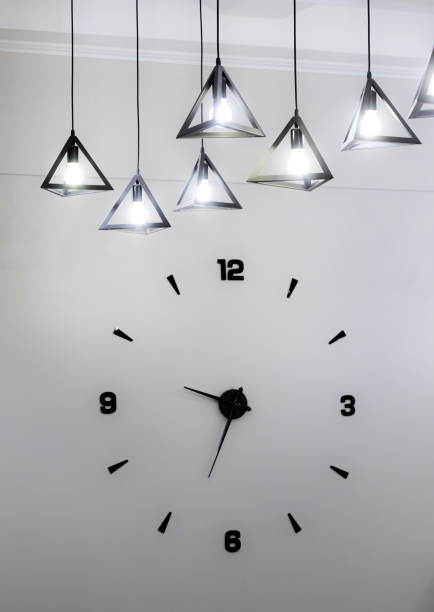 istock Minimalistic design of a wall clock with black numbers and a light bulb 1345934282