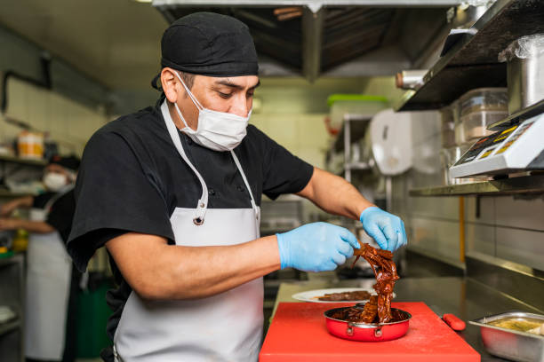 Male chef plating food in plate while working in commercial kitchen - Buenos Aires - Argentina