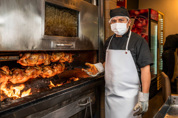 cocinero mirando a la cámara junto a la parrilla con una pila de pollo a la parrilla en un pincho - rotisserie chicken meat dinner fotografías e imágenes de stock