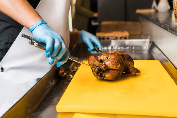 Unrecognizable cook preparing to cut up a chicken that was grilled for a customer of a restaurant.