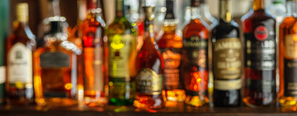 bellissimo bokeh da una fila di bottiglie alcoliche in retroilluminazione. scatto panoramico. - liquor store foto e immagini stock