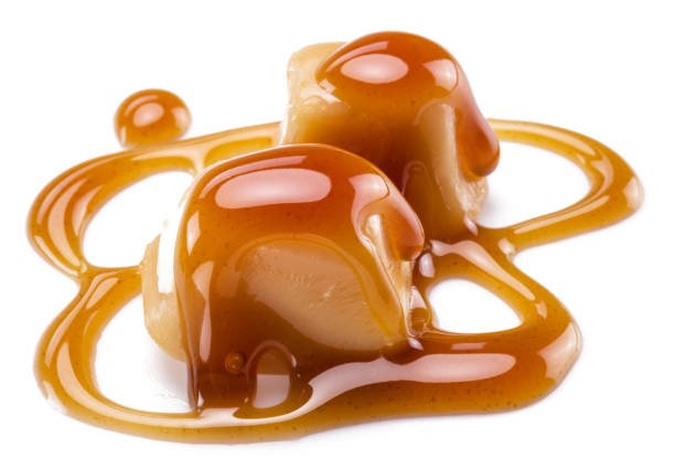 istock Caramel candies covered with melted sugar caramel isolated on white background. 1345935389